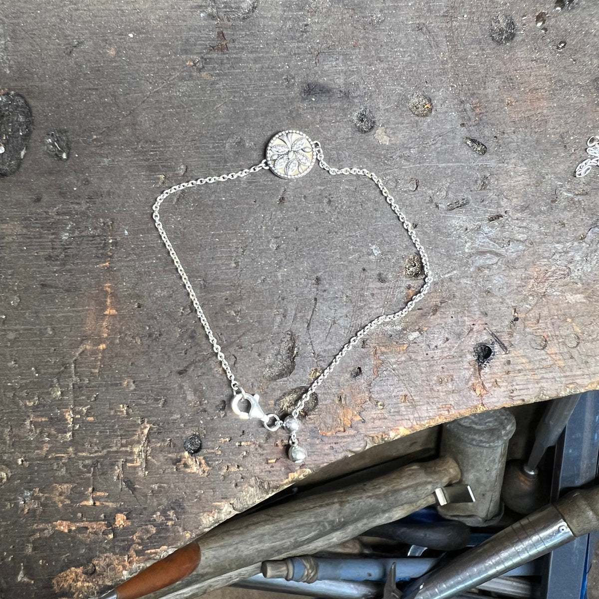 Silver necklace on a workbench with tools in the background