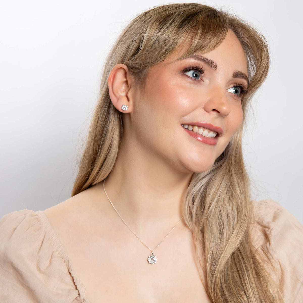 Woman wearing a necklace and earring on a plain background