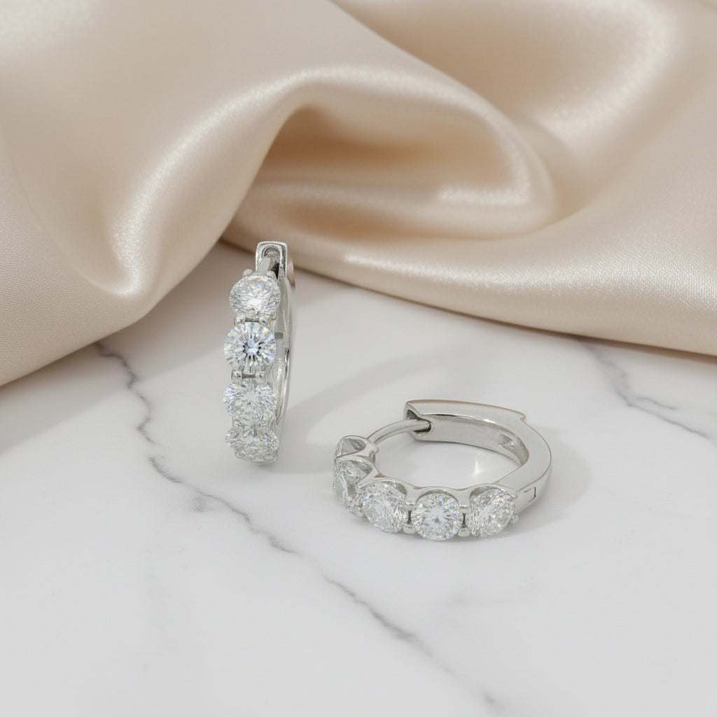 Pair of silver hoop earrings with clear stones on a soft fabric background