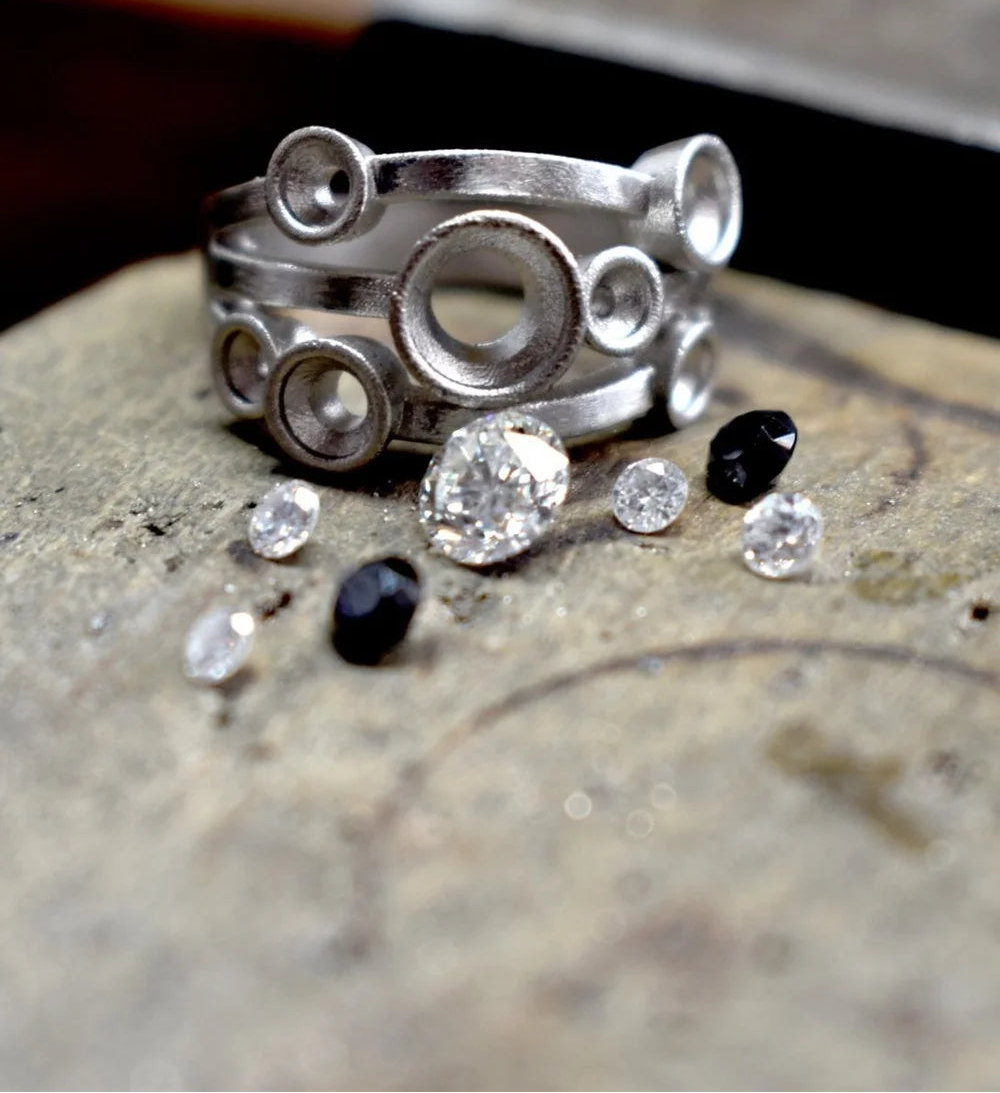 Silver ring with embedded stones on a textured surface