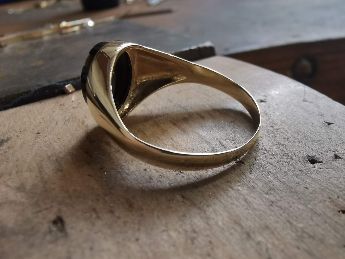 Gold ring on a textured surface with tools in the background