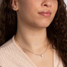 Close-up of a woman wearing a delicate necklace with a small pendant.