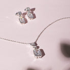 Silver necklace and earrings with gemstones on a pink background
