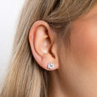 Close-up of an ear wearing a diamond stud earring with a blurred background
