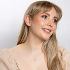 Woman wearing a necklace and earring on a plain background