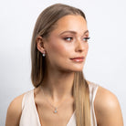 Woman wearing a necklace and earrings on a plain background