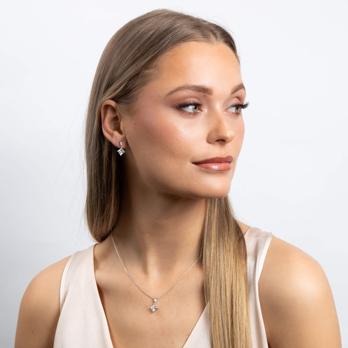 Woman wearing a necklace and earrings on a plain background