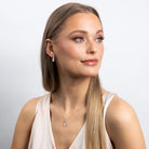 Woman wearing a necklace and earrings on a plain background