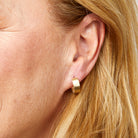 Gold hoop earring worn by a person with blonde hair.