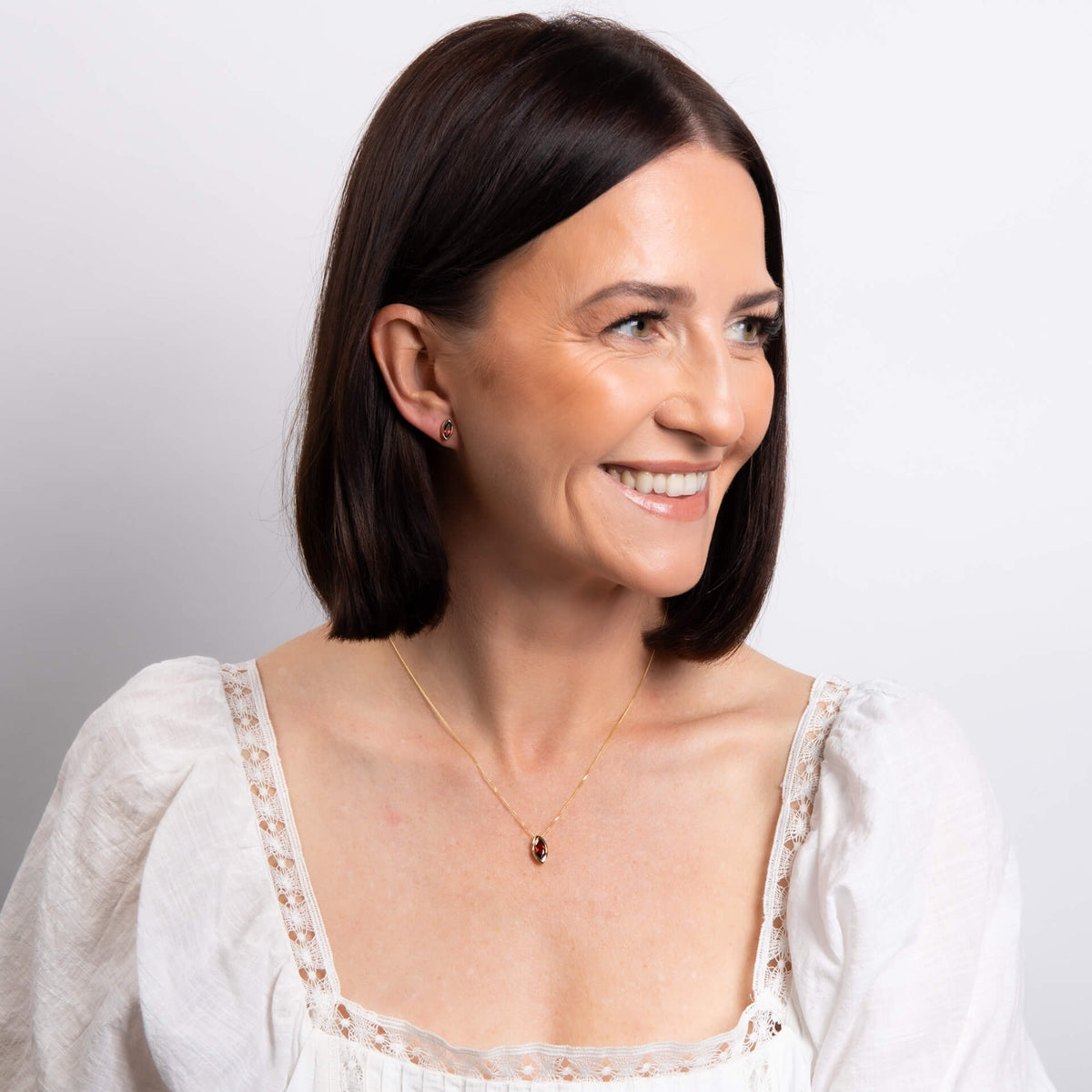 Woman wearing a white blouse with lace details on a plain background