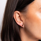 Close-up of an ear wearing a small earring with dark hair and skin.