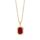 Gold pendant with a red gemstone on a white background