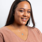 Woman wearing a pink top and necklace with a white background