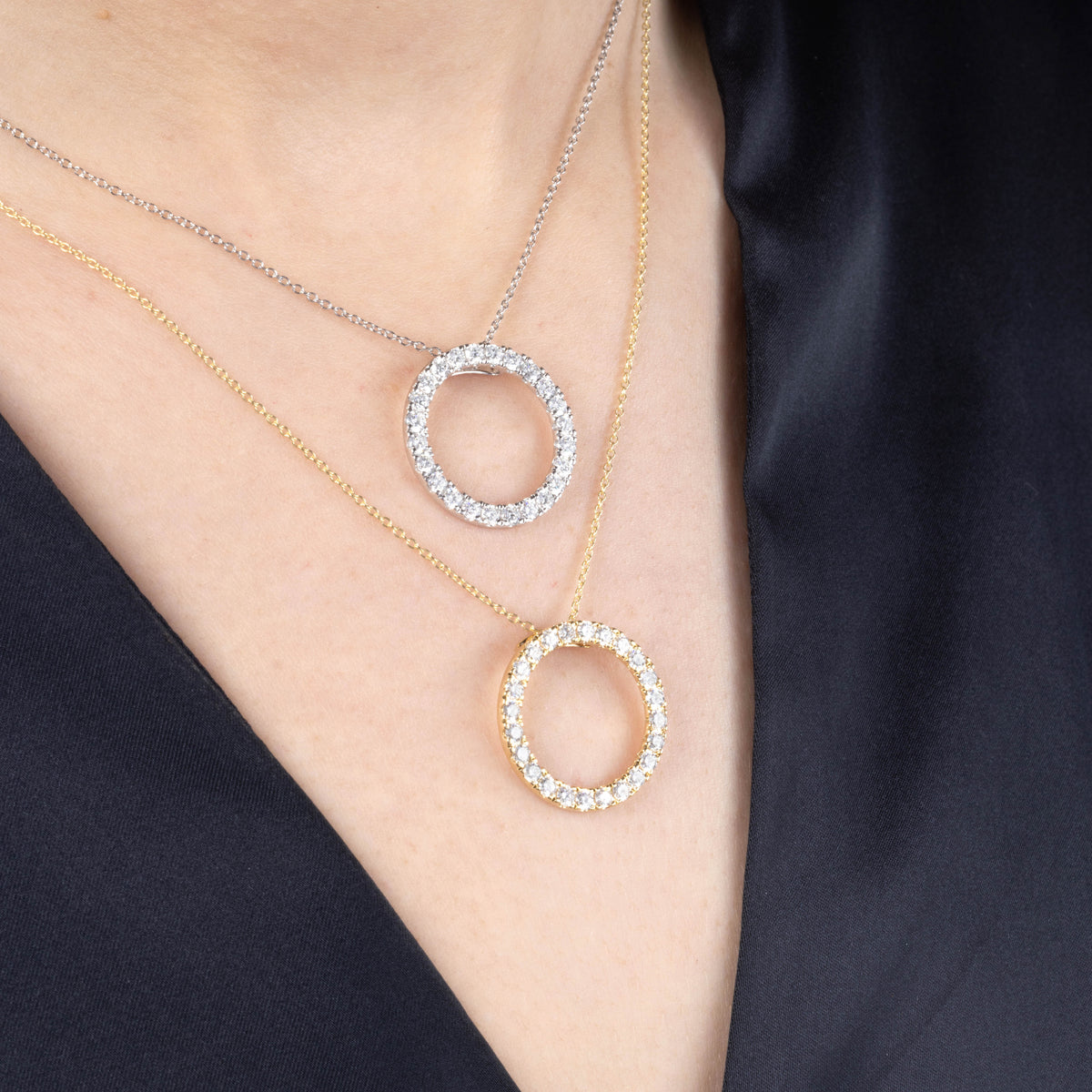 Two diamond necklaces on a person's neck against a dark background