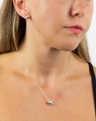 Close-up of a woman wearing a silver necklace with a heart pendant.