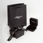 Black jewelry box with black ribbon and Diamonfire branded paper bag on a white background